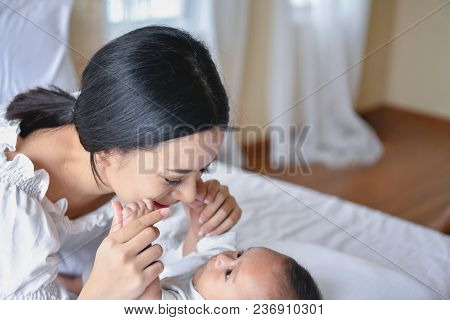 Newborn Concept. Mother And Child On A White Bed. Mom And Baby Boy Playing In Bedroom. Parent And Li