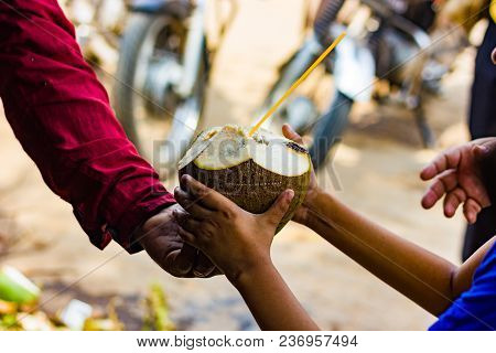 Coconut Water In Coconut With Straw Handed Over To A Kid By Seller. Natural Tropical Drink.