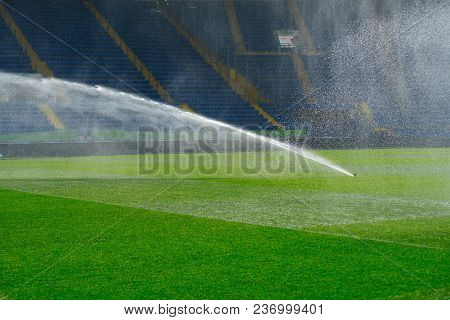 Irrigation Turf. Sprinkler Watering Football Field. System Working On Fresh Green Grass On Football
