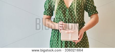 A Girl Holds A Gift Box On A White Background. Banner, Copy Space.