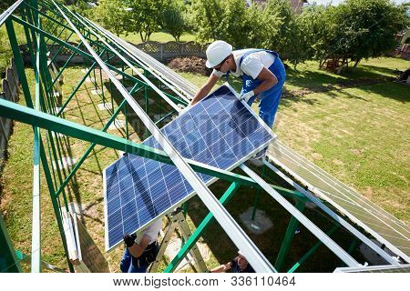 Professional Mounters Team Installing Solar Panels On Roof Green Carcass While Sunny Day. Innovative