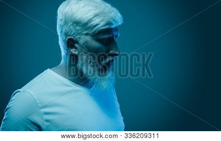 Side View Of Serious Mystical Tensed Guy With Albinism Looking Away Thoughtfully On Blue Dark Neon B