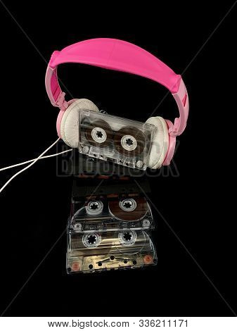 Plastic Cassette And Audio Headphones. Music Cassette On A Black Background. Concept: Music, Meloman