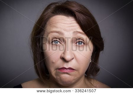 Woman Grimaces In Front Of Camera On Black Background