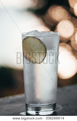 Cocktail Glass With Gin Tonic And A Lime And Ice Cubes On A Balcony With Scenic And Magnificent View