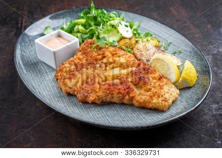 Deep fried Wiener schnitzel from veal topside with fried potatoes and lettuce as closeup modern design plate 
