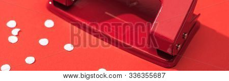 Panoramic Shot Of Holepunch With Paper Circles On Red Background