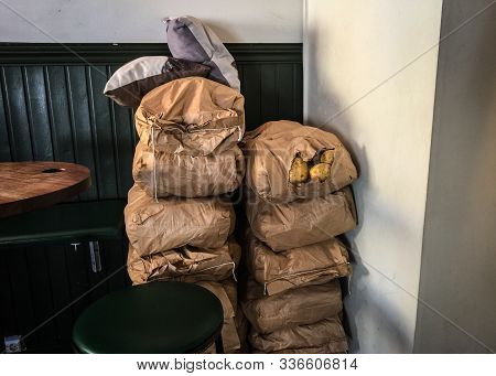 Two Large Piles Of Bagged Potatoes Sit In The Corner Of A Restaurant