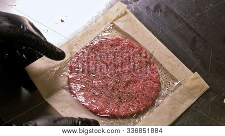 Cook Makes Meat Medallions For Burgers. Chef In Black Food Gloves Makes Cutlet. Cutlets Are Leveled 