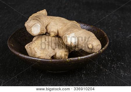 Group Of Two Whole Fresh Brown Ginger In Glazed Bowl On Grey Stone