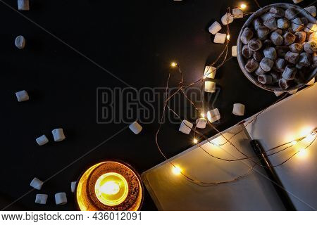 Cup With Hot Winter Cacao And Marshmallows At Night. Christmas Lights. Tea Light Candles. Empty Note