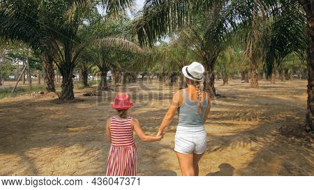 Mom And Daughter For A Walk. Woman Tourist With Plait Walks Looking Around At Growing Young Trees Wi