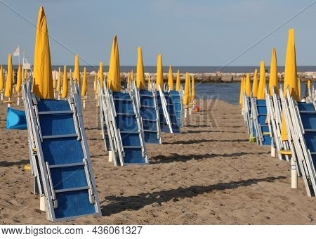 Beache With Many Already Closed Umbrellas And Deck Chairs Closed At The End Of The Bathing Season