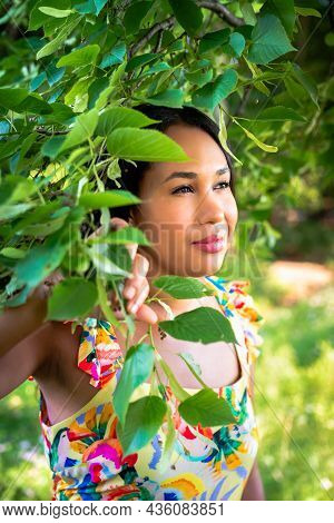 A Beautiful Mixed Race African American Woman In Yellow Floral Dress Standing In The Forest On A Sun
