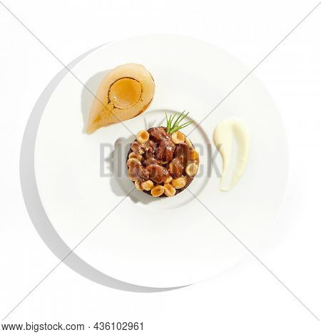 Chocolate tartlet with nuts toffee on white plate. Delicious dessert - Caramel nut tart with pear. Traditional pastry - Butterscotch tartlet with hazelnut, almond and pecan. Autumn dessert