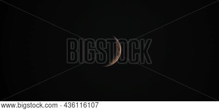 A Wide Dramatic Night Time Closeup Shot Of A Crescent Moon With Orange And Yellow Hues Showing Great