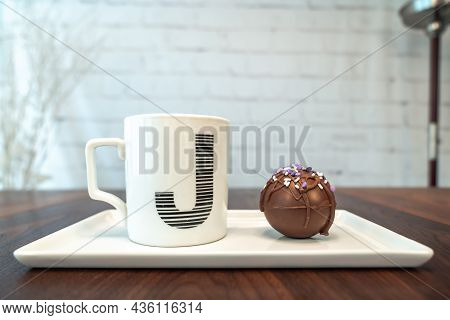 Side View Of A Hot Cocoa Or Chocolate Bomb Covered In Drizzled Brown Chocolate And Purple And White 