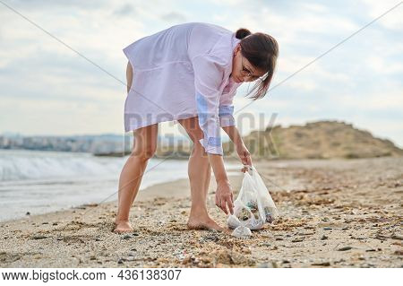 Active Woman Tourist Relaxing On The Beach Collecting Plastic Trash In A Bag