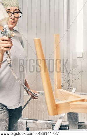 Pretty Woman Worker Paints Wooden Chair Base In Transparent Varnish With Spray Gun On Rack Support I