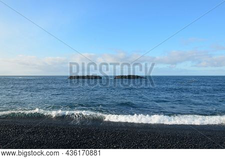 Black Sand Beach With An Undertow With Waves Pulling Back.