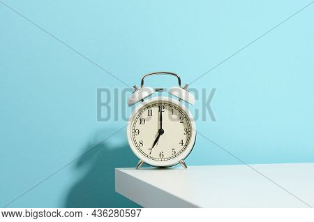 Round White Alarm Clock On The Table. Time Seven In The Morning, Get Up Early, Change Hours
