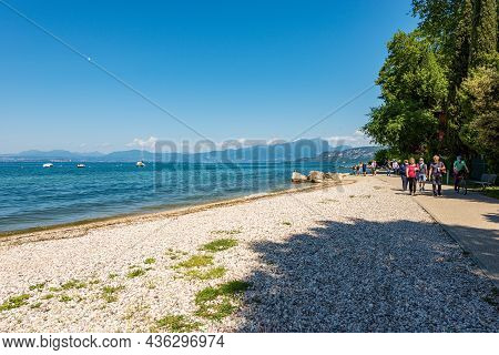 Bardolino, Italy - May 26, 2021: Coast Of Lake Garda With A Beach And Bicycle And Pedestrian Lane Th