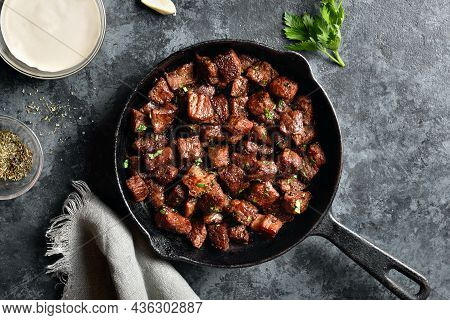 Garlic Butter Steak Bites In Cast Iron Pan Over Blue Stone Background. Top View, Flat Lay