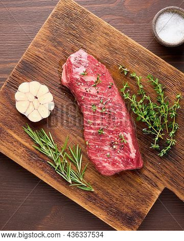 Raw Tender And Marbled Striploin Steak With Salt, Garlic Clove And Rosemary And Thyme On Wooden Boar