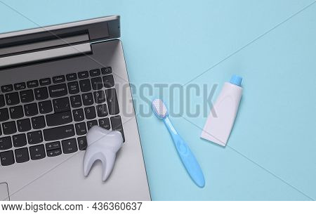 Fake Tooth, Toothbrush, Toothpaste And Laptop On Blue Background. Teeth Care, Medicine Concept. Top 