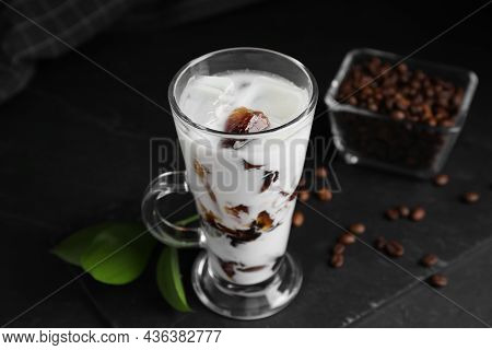 Glass Cup Of Milk With Delicious Grass Jelly And Coffee Beans On Black Table, Closeup