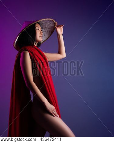 Asian Woman In Red Cape And Asian Hat Posing On Bright Neon Background