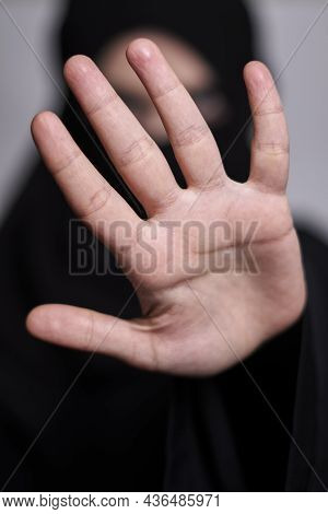 A Muslim Woman In Traditional Black Clothing Nikab Showing Stop Hand Gesture. Role Of Women In Islam