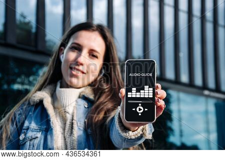Audio Tour Online App On Digital Mobile Smartphone. Happy Young Student Woman Holding Phone Listenin