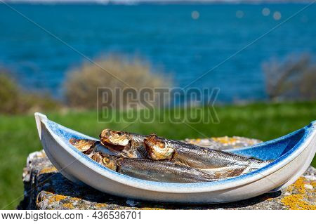 Smoked Sprattus Or Sprats Sea Fish Served Outdoor With View On Blue Sea Water