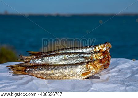 Smoked Sprattus Or Sprats Sea Fish Served Outdoor With View On Blue Sea Water
