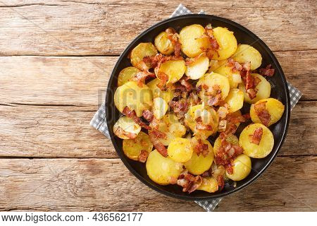 German Pan Fried Potatoes Or Bratkartoffeln With Bacon And Onion Close Up In The Plate On The Table.