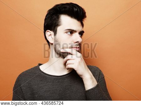 young handsome man posing over orabge background
