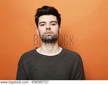 young handsome man posing over orabge background