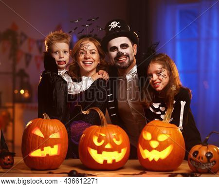 Young Family Mother Father And Children In Halloween Costumes Celebrating All Hallows Eve At Home