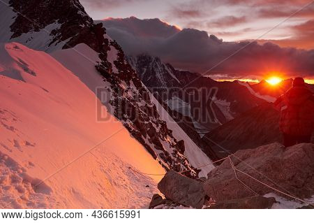 Sunset In Mountains. Reflection Of Red Sun On Mountain Snow Peaks And Clouds. Altai, Belukha Area