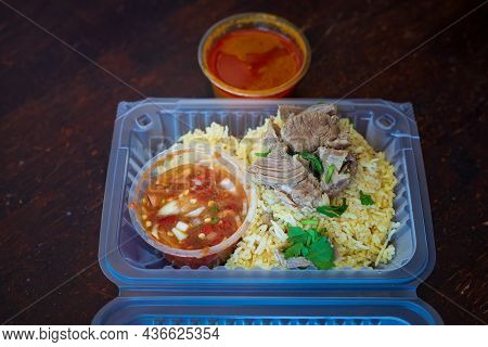 Roasted Meat Served With Rice And Chillies Tamarind Sauce And Curry Gravy In A Take Out Container. M