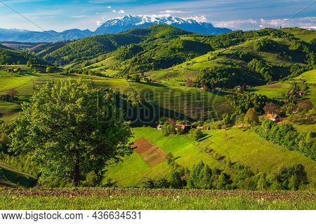 Amazing Spring Countryside Landscape, Houses And Farmlands On The Hills. Beautiful Snowy Mountains I