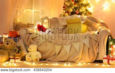 Festive Home interior - wew year or christmas decoration. At night, the room glows with festive lights. A lots of gifts and decorations. Winter holiday concept