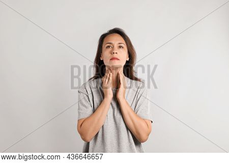Mature Woman Doing Thyroid Self Examination On Light Background