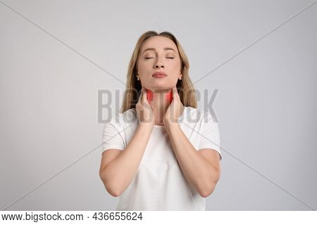 Young Woman Doing Thyroid Self Examination On Light Grey Background