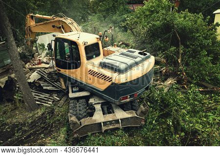 Yellow Hydraulic Excavator Breaks And Knocks Down Green Trees On Site, Freeing Up Area For Building 