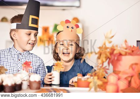 Kids Sitting On Festive Table And Celebrating Thanksgiving Day. Children In Paper Turkey Hat And Pil