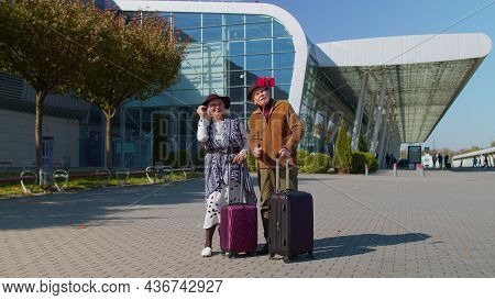 Elderly Old Husband And Wife Retirees Tourists Near Airport Terminal Get Video Call Use Mobile Cell 