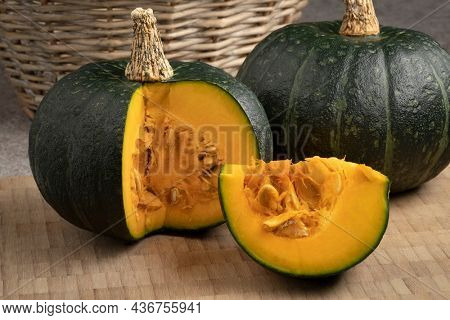 Fresh green whole Kabocha pumpkin and a cut close up on a cuttingboard