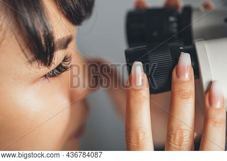 Female Scientist Looking Through A Microscope, Doing Research. Close Up. Experiment In Pharmacology